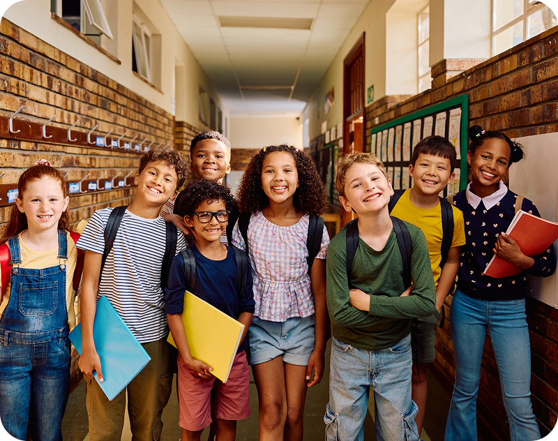 Group of smiling children in school hallway.
