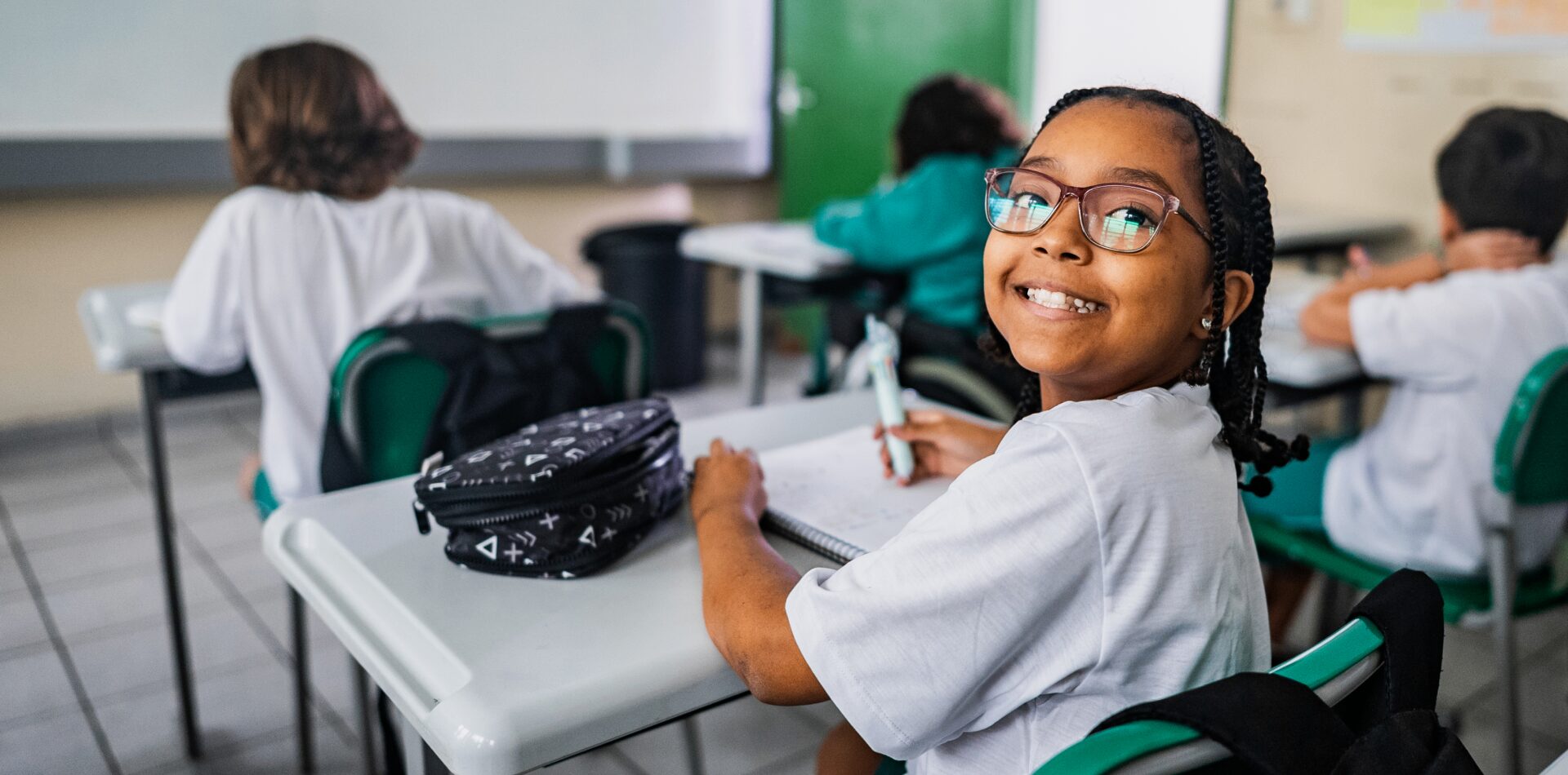 Smiling student sitting at a classroom desk.